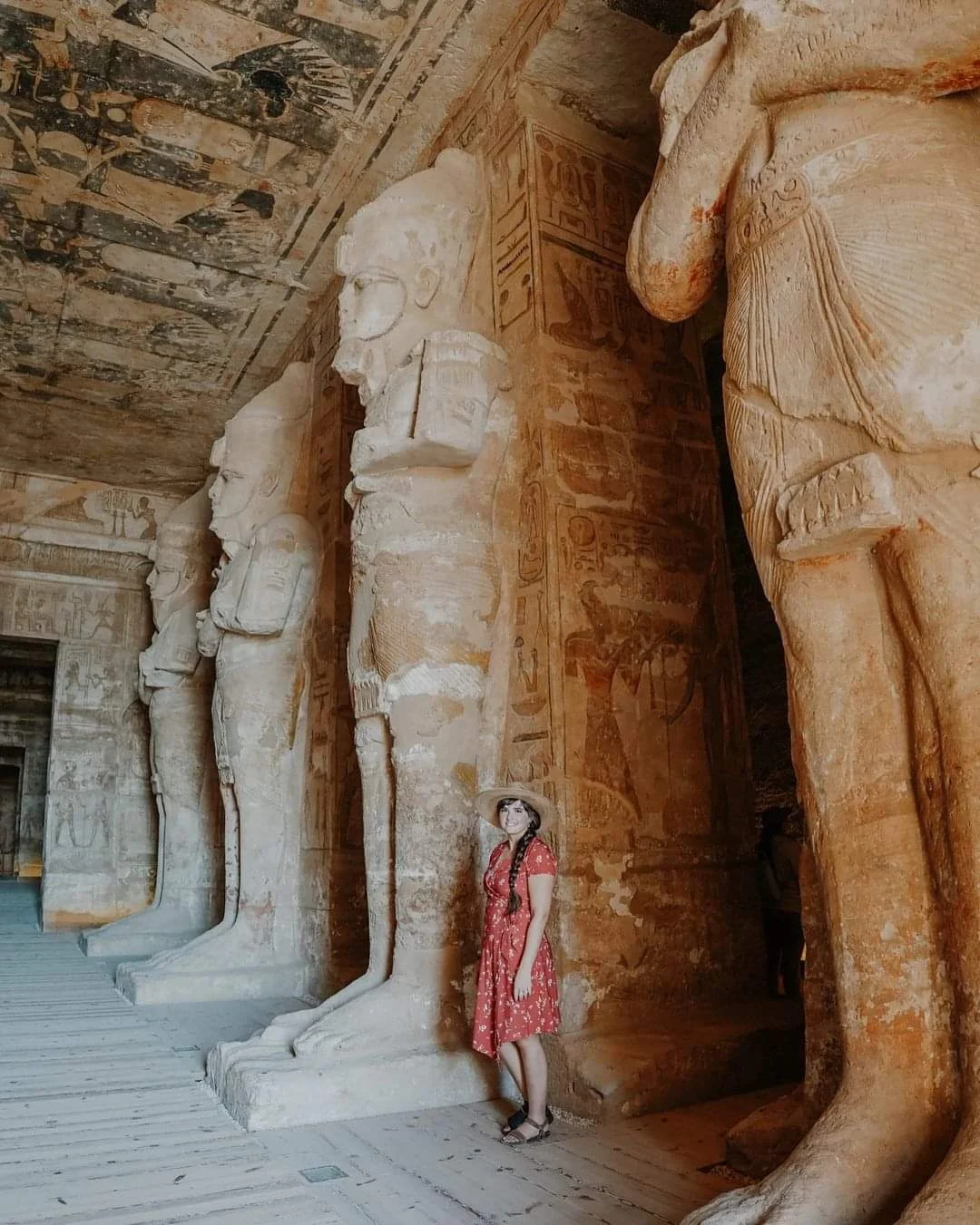 Touristin steht zwischen den monumentalen Osiris-Statuen im Inneren des Tempels von Abu Simbel in &Auml;gypten.