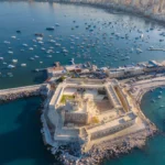 Luftaufnahme der Festung Qaitbay in Alexandria mit Booten im Mittelmeer und Blick auf die Stadt.