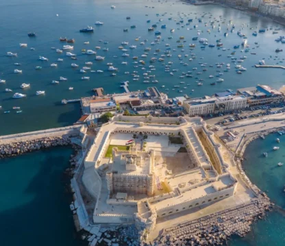 Luftaufnahme der Festung Qaitbay in Alexandria mit Booten im Mittelmeer und Blick auf die Stadt.