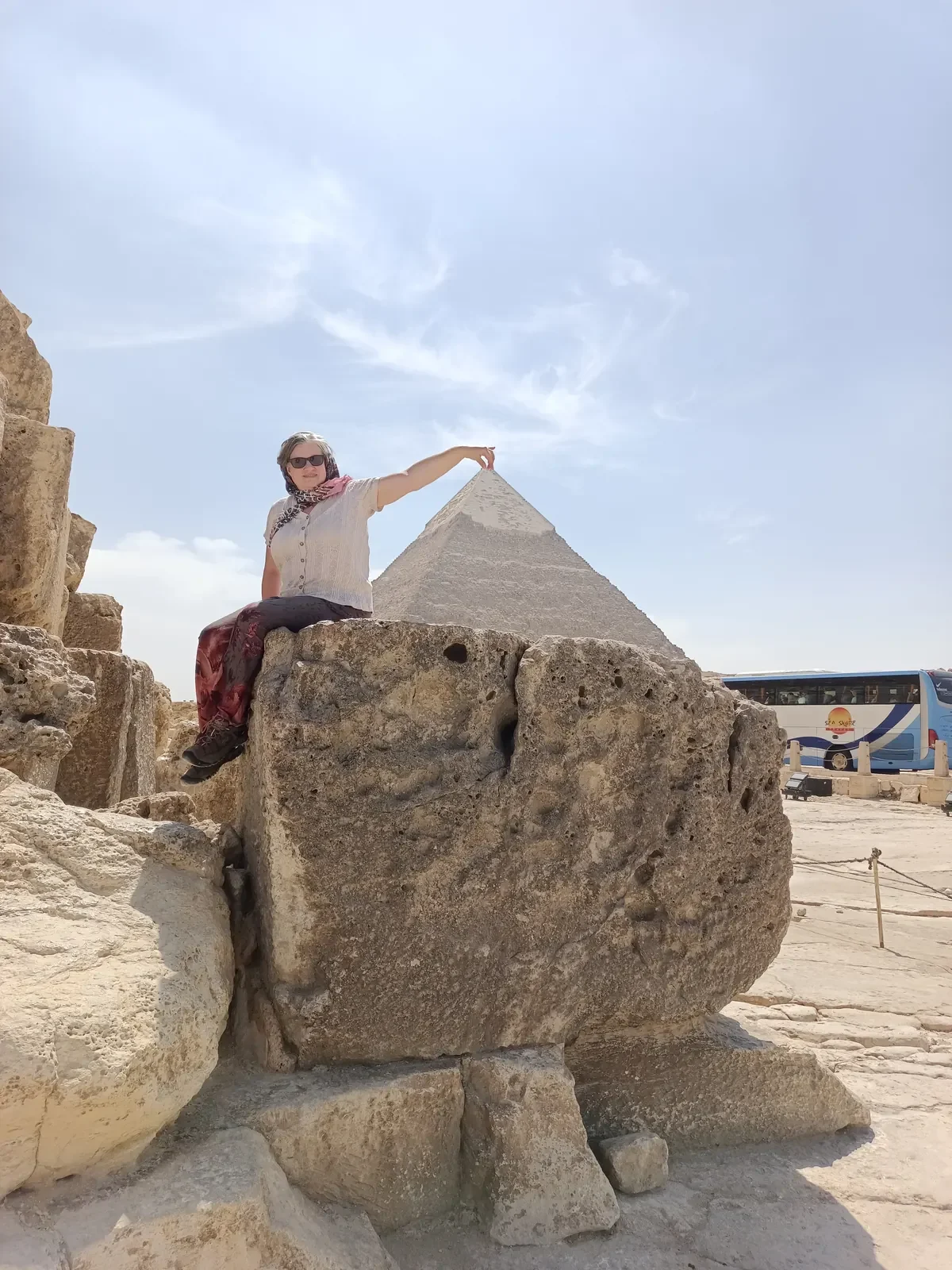 Touristin sitzt auf einem Steinblock vor der Cheops-Pyramide in Gizeh.