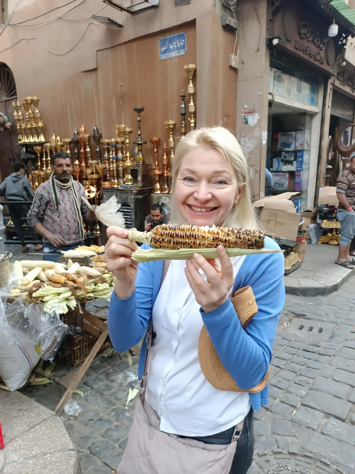 Touristin probiert gegrillten Maiskolben von einem Stra&szlig;enstand in der Altstadt von Kairo, &Auml;gypten.