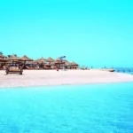 Sandstrand mit Strohschirmen und türkisfarbenem Meer in Hurghada