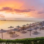 Sonnenuntergang am Roten Meer in &Auml;gypten mit Strandschirmen und Steg