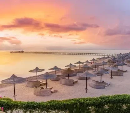 Sonnenuntergang am Roten Meer in &Auml;gypten mit Strandschirmen und Steg