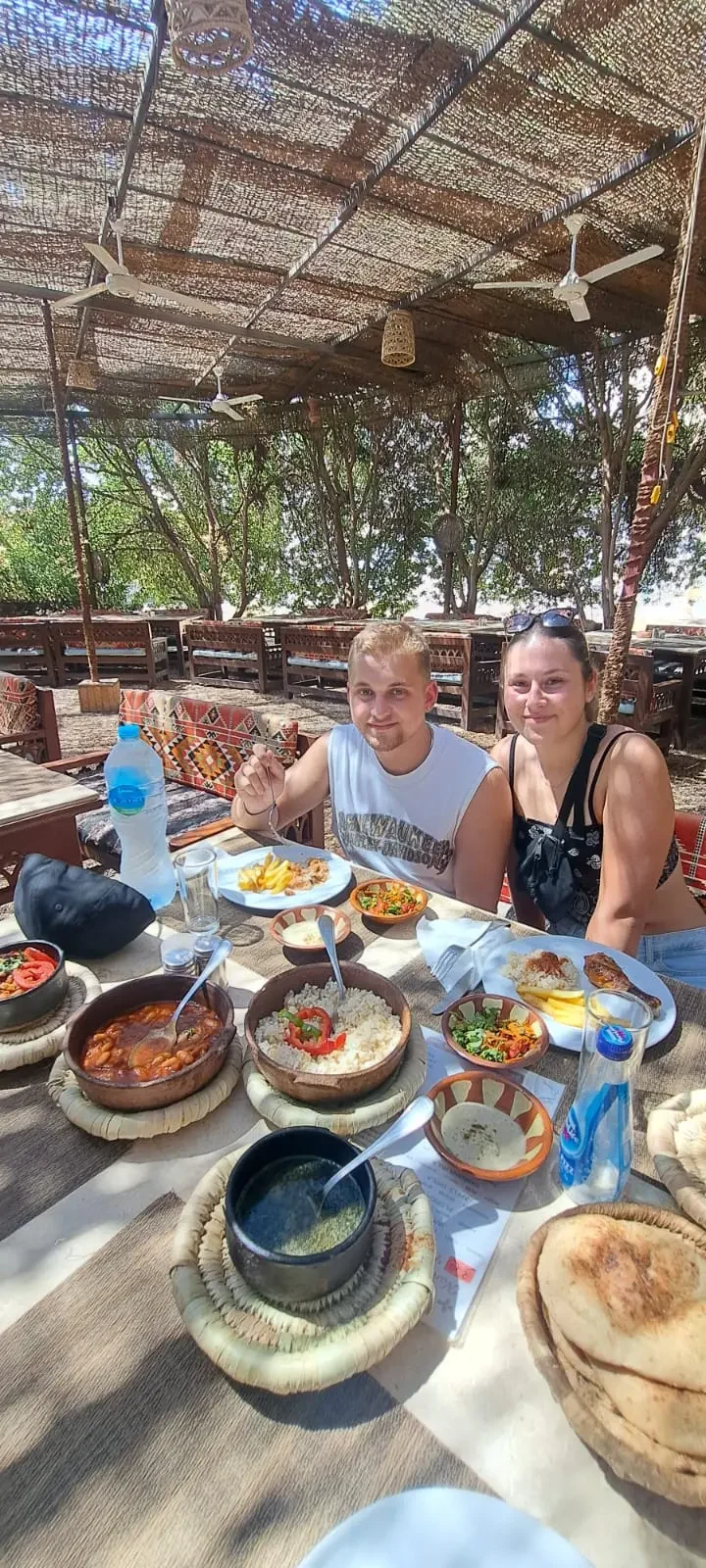 Touristen genie&szlig;en traditionelles &auml;gyptisches Essen in einem Beduinen-Restaurant unter schattigem Dach.