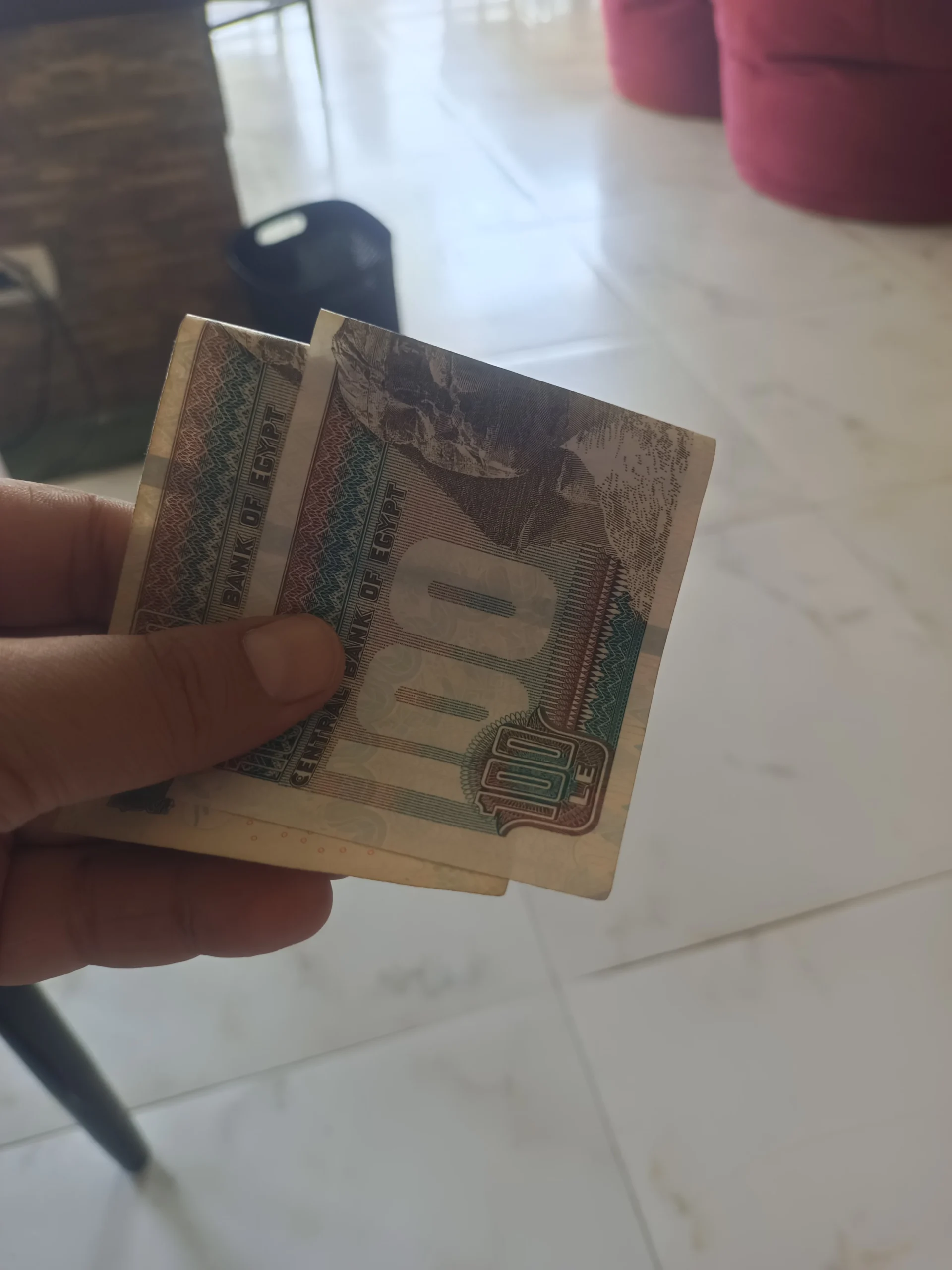 Hand h&auml;lt zwei &auml;gyptische 100-Pfund-Banknoten der Central Bank of Egypt.