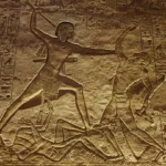 Alt&auml;gyptisches Steinrelief zeigt einen Pharao im Kampf mit Feinden, umgeben von Hieroglyphen.