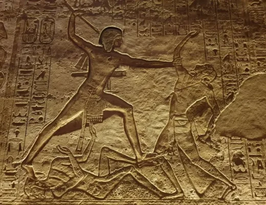 Alt&auml;gyptisches Steinrelief zeigt einen Pharao im Kampf mit Feinden, umgeben von Hieroglyphen.