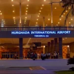 Eingangsbereich des Flughafens Hurghada, Terminal 1, bei Abenddämmerung beleuchtet.