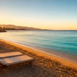 Sonnenaufgang über dem Strand von Hurghada mit Liegestühlen am türkisfarbenen Roten Meer im Dezember