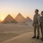 Paar beobachtet den Sonnenuntergang &uuml;ber den Pyramiden von Gizeh bei Kairo