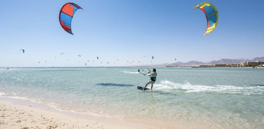 Kitesurfer im t&uuml;rkisfarbenen Wasser vor Hurghada mit zahlreichen Kites am Himmel.
