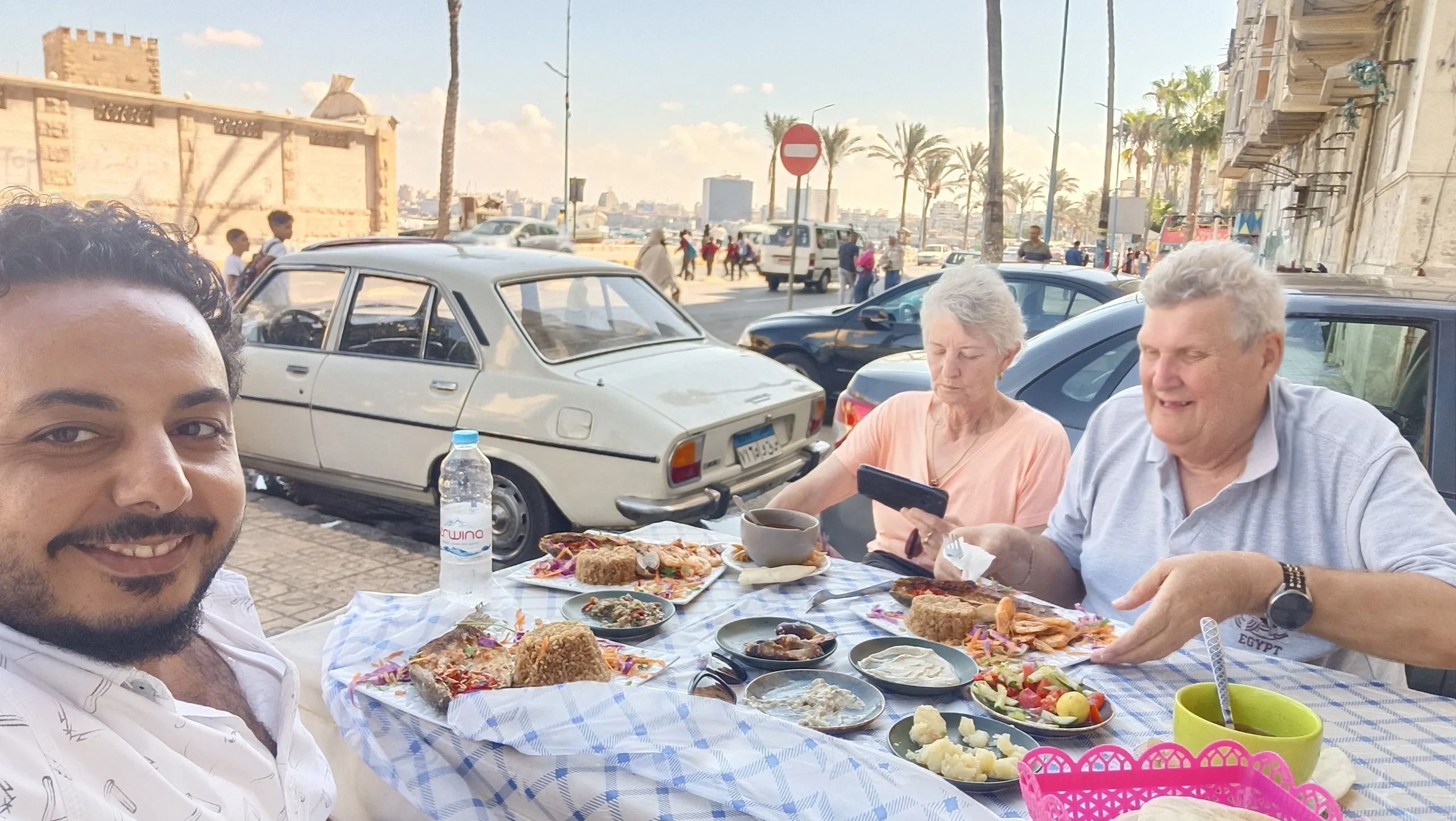 Touristen genießen frisch gegrillten Fisch bei einem Streetfood-Essen an der Küste von Alexandria.