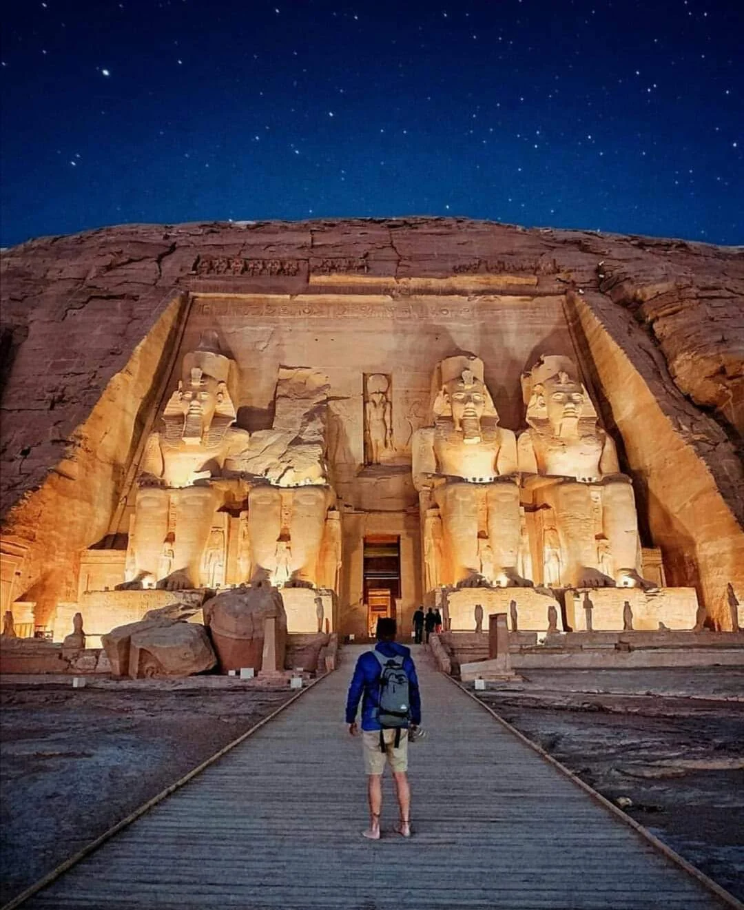 N&auml;chtlicher Blick auf den beleuchteten Tempel von Abu Simbel mit den vier Ramses-Kolossalstatuen unter Sternenhimmel.